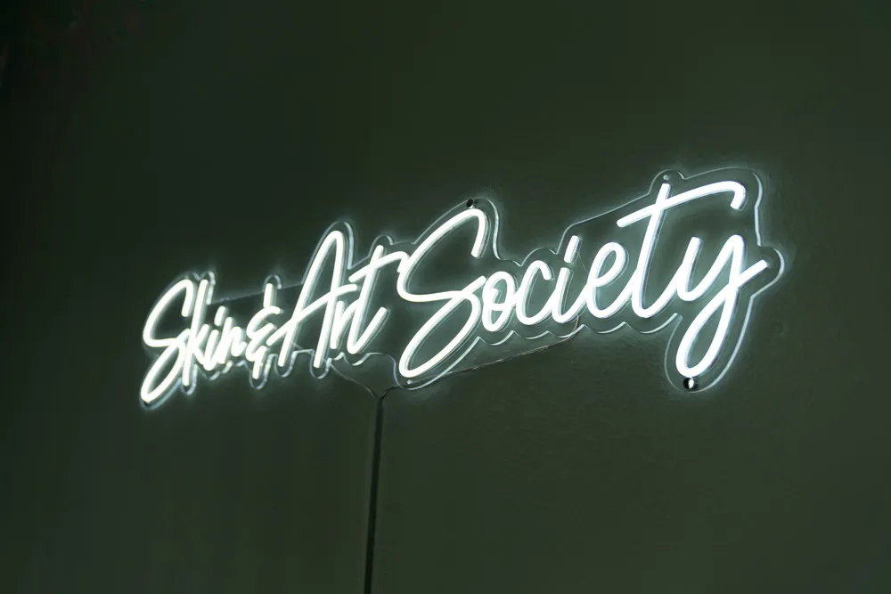 Studio-Innenraum Skin & Art Society Münchberg mit Behandlungsstuhl und Tattoo-Sketches an der Wand
